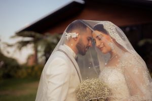 Intimate wedding portrait of a couple beneath a lace veil holding baby's breath flowers.