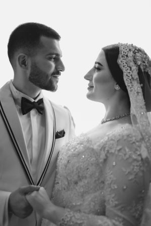 Black and white close-up portrait of newlyweds sharing a tender moment in formal attire.