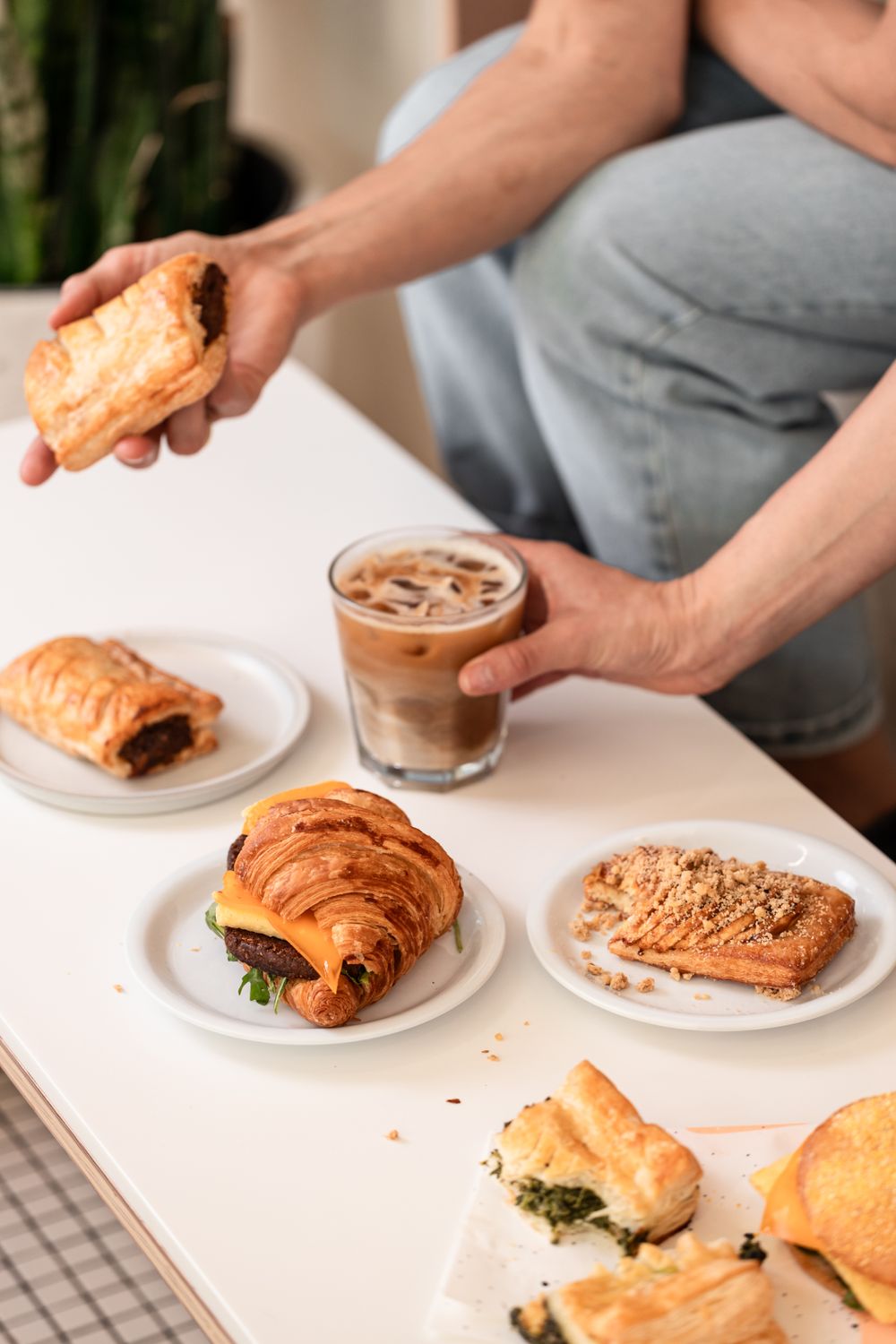 The table features a croissant sandwich, a streusel pastry, and other vegan baked goods.
