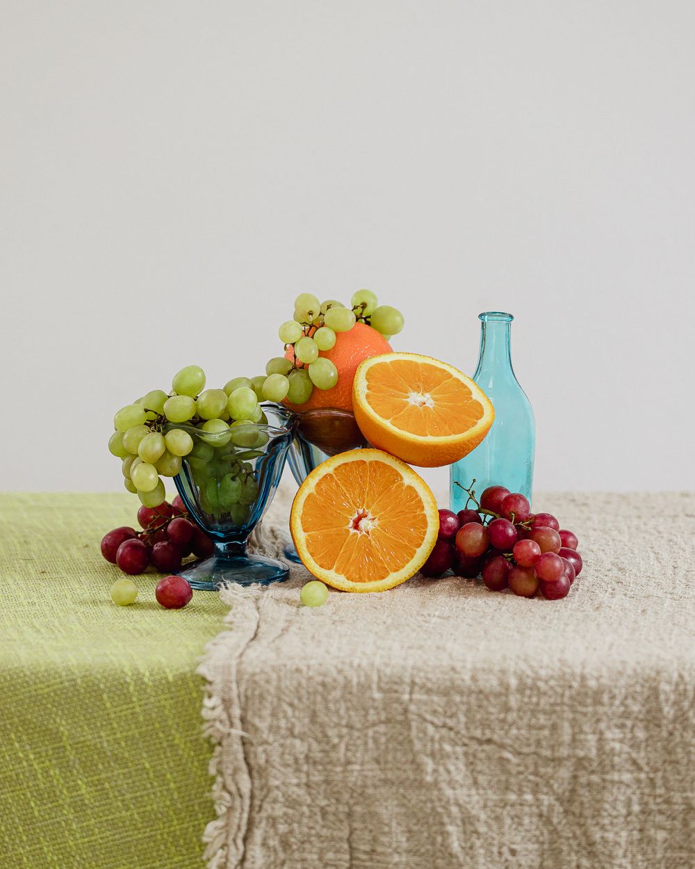 Fruit tablescape styling and food photography by Vancouver, BC food photographer Rosslyn Maria. Features blue glassware, oranges, and grapes