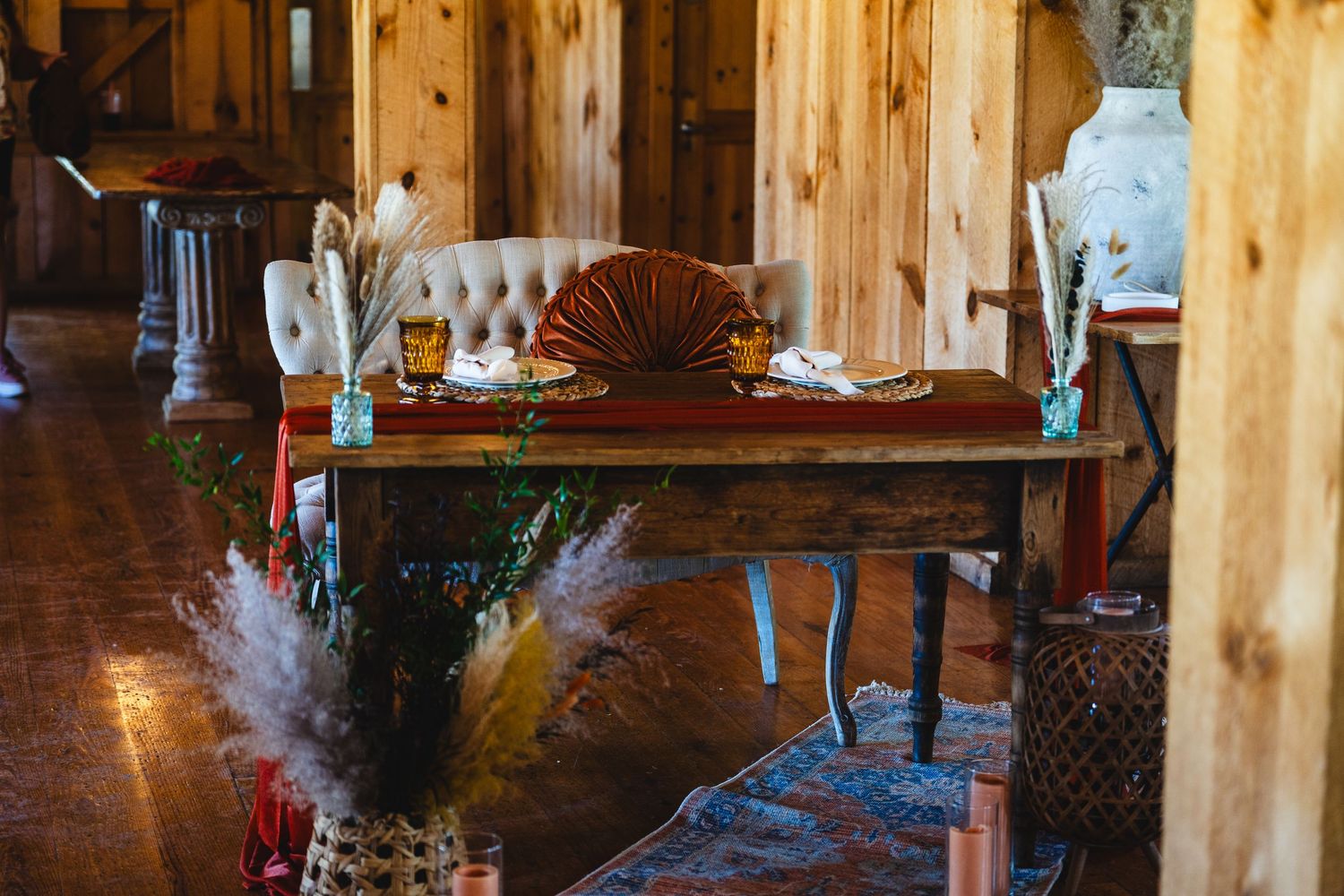 Vintage wood dining table decorated with pampas grass and seashells in a rustic cabin interior.