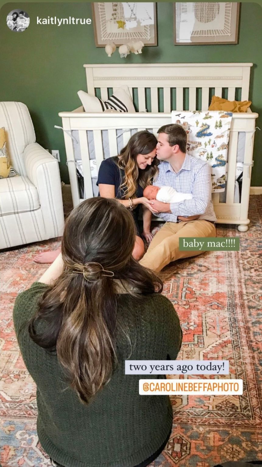 Photographer capturing couple with newborn baby sitting in front of green nursery crib.