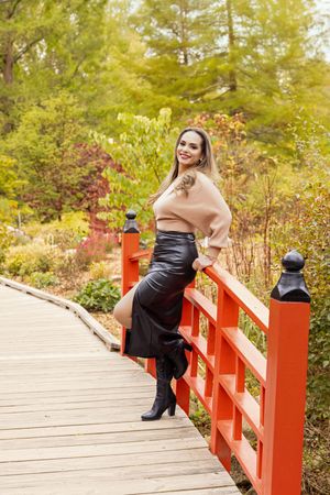 A sequence of photos shows someone in black and tan posing on a red-railed wooden bridge in an autumn garden setting.