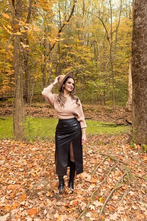 Artistic autumn photoshoot in a forest with fallen leaves and golden foliage creating a warm seasonal backdrop.