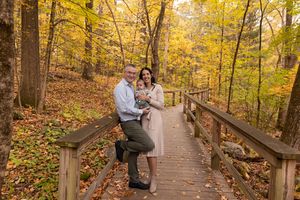 Couple enjoying a romantic autumn walk along a wooden boardwalk trail surrounded by golden fall foliage.