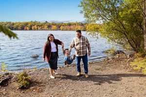 Family enjoying an autumn day together by the lake shore with golden foliage in the background.