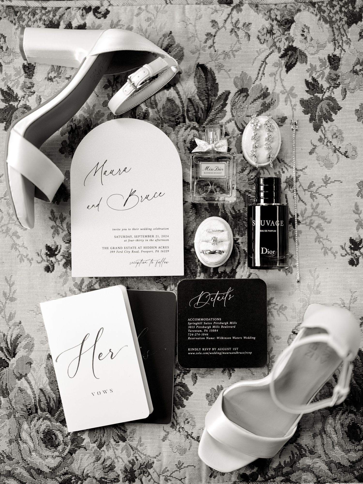Black and white wedding invitation suite with white heels and floral background styling.