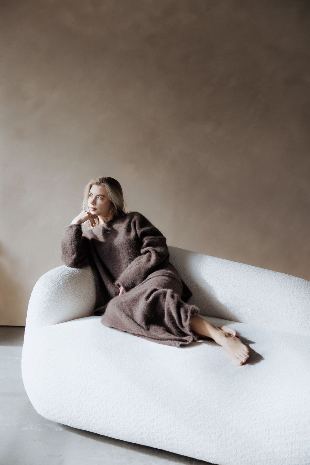 Artistic series of moody photographs showing a person lying on a white couch in various reclining poses.