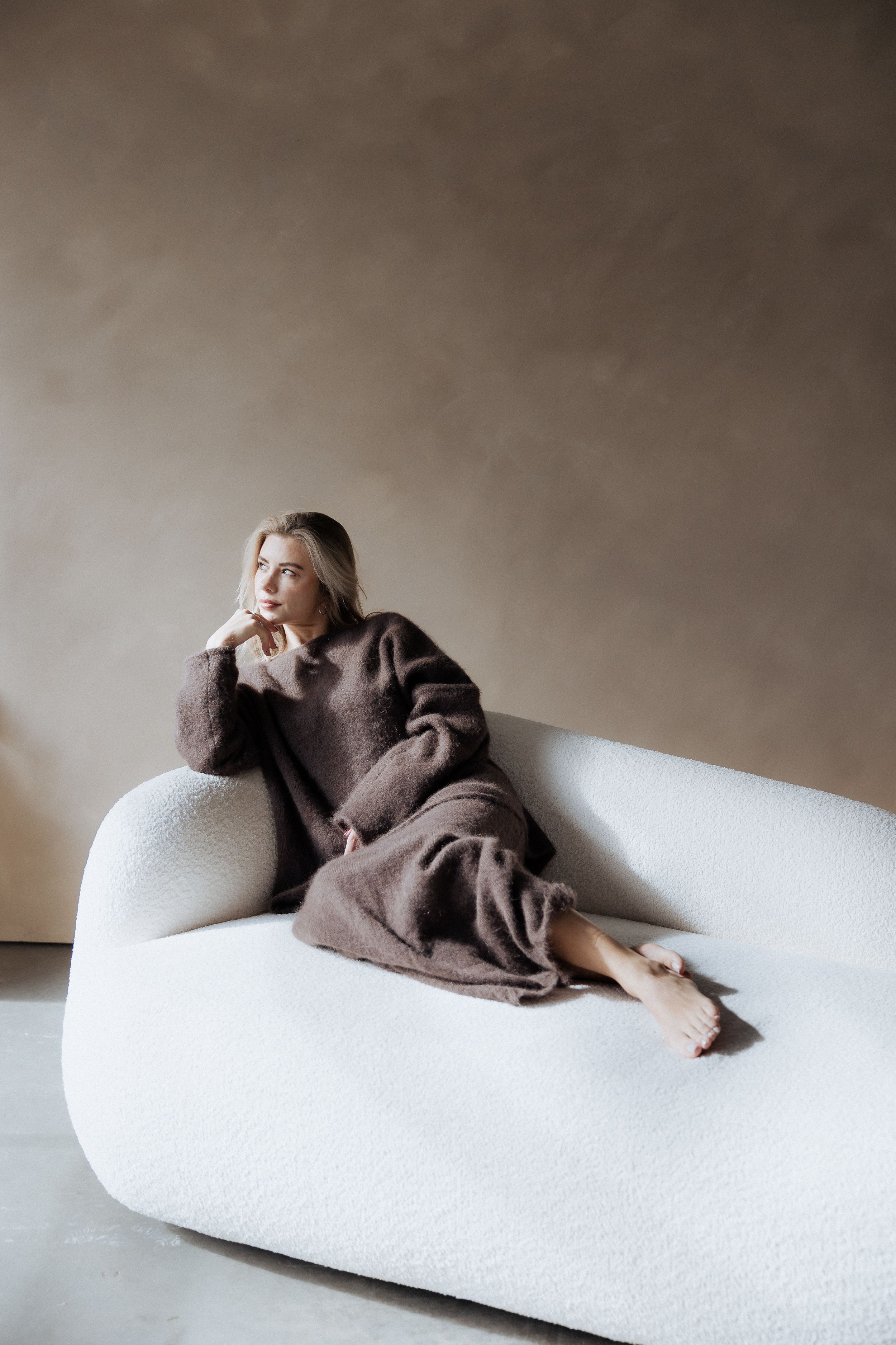 Artistic series of moody photographs showing a person lying on a white couch in various reclining poses.