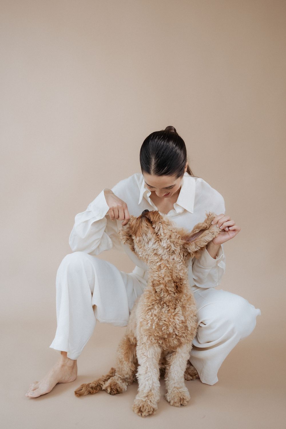 Playful interaction with fluffy golden dog while wearing white outfit.