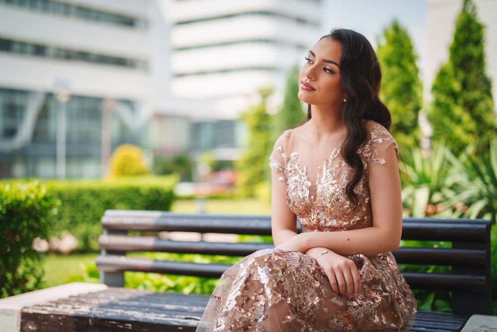 Dreamy outdoor portrait featuring intricate rose gold dress against modern architectural setting.