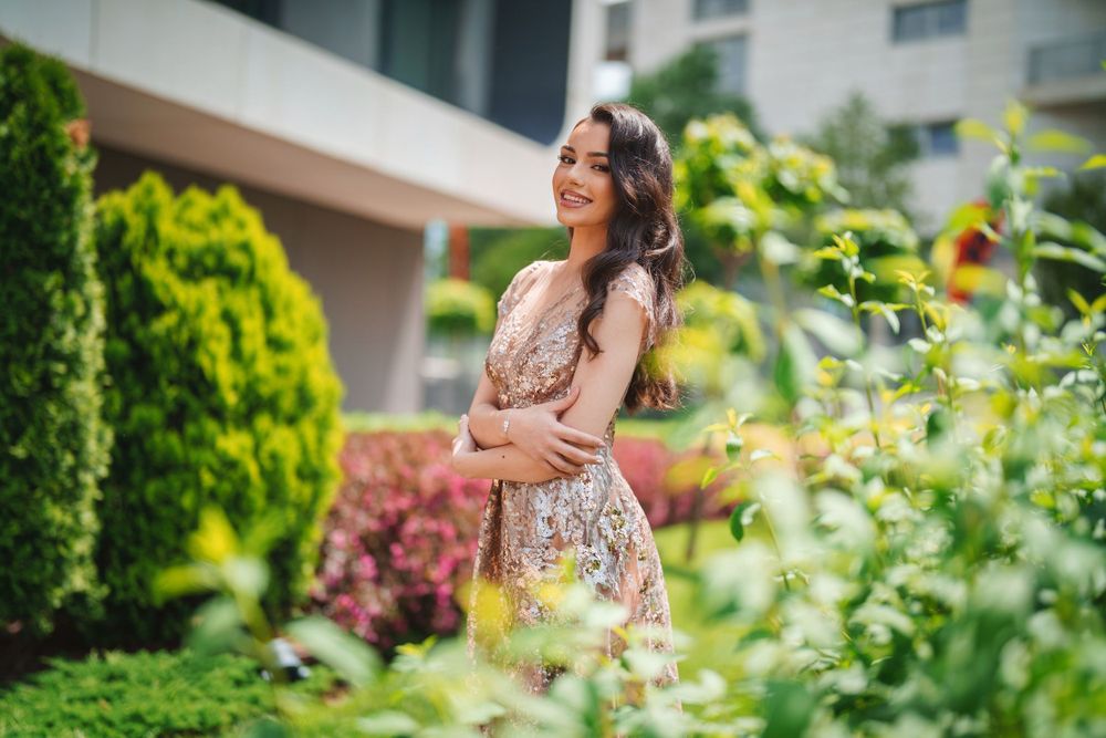 Candid garden portrait featuring delicate rose gold sequined dress amid green foliage.