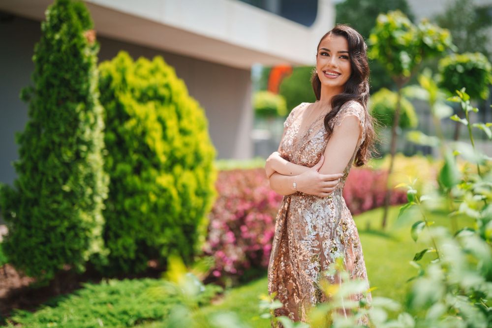 Joyful garden portrait featuring sparkly formal dress against vibrant green landscaping.