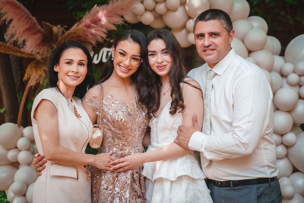 Four people pose closely together at a celebration with balloon decorations in the background.