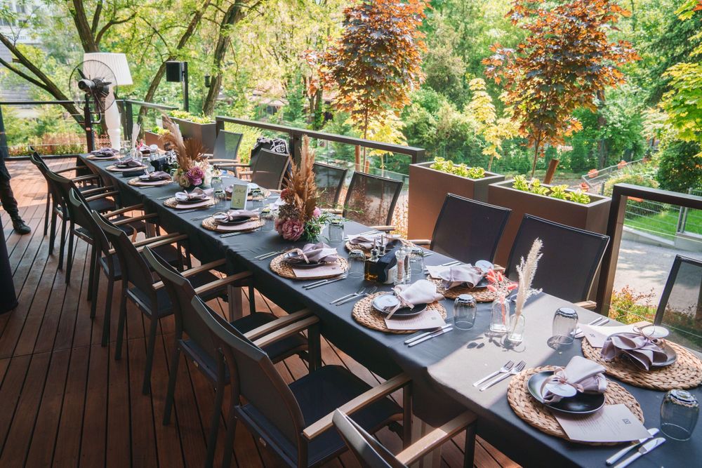 An elegant outdoor dining table set up on a wooden deck with place settings and decorations.