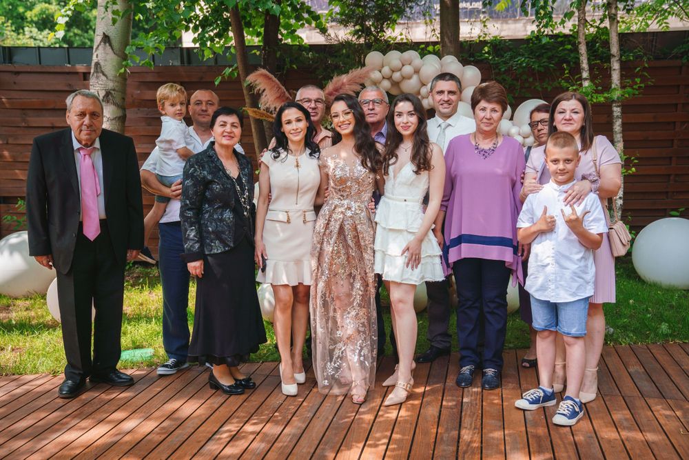 Large group photo of celebration attendees on a wooden deck with balloons and garden backdrop.