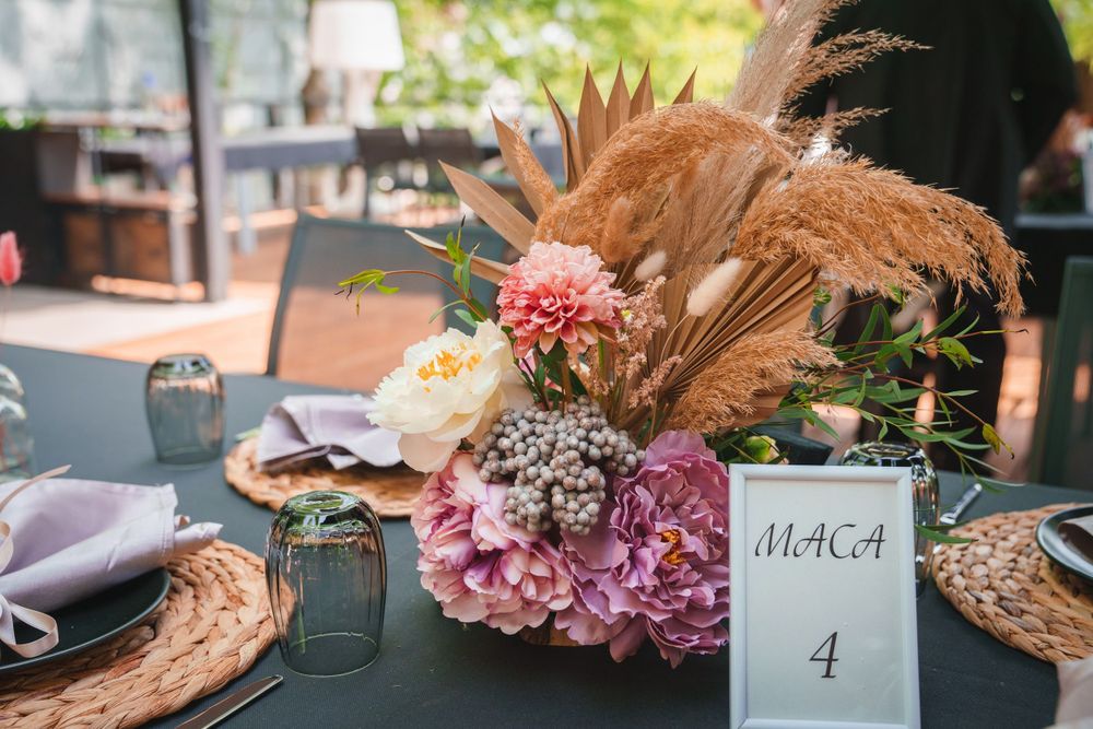 Table setting with pink flowers, pampas grass, and place card number 4 at an outdoor event.