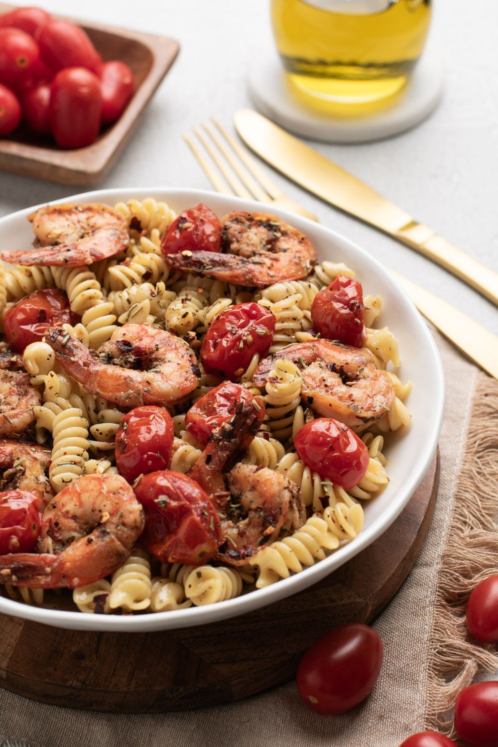 Pasta dish with grilled shrimp and cherry tomatoes served on a white plate.