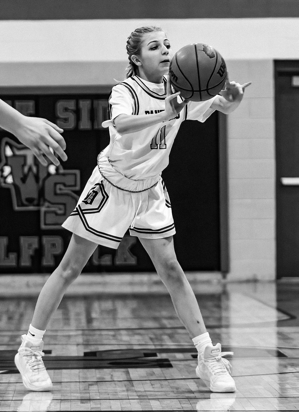Basketball player in white uniform stretches to catch the ball during game play.