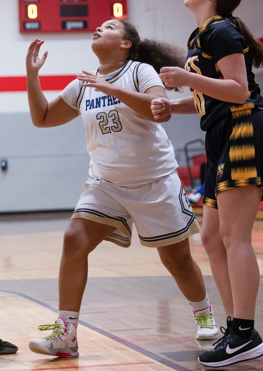 Basketball player in a white Panthers jersey positions for a rebound during an intense game moment.