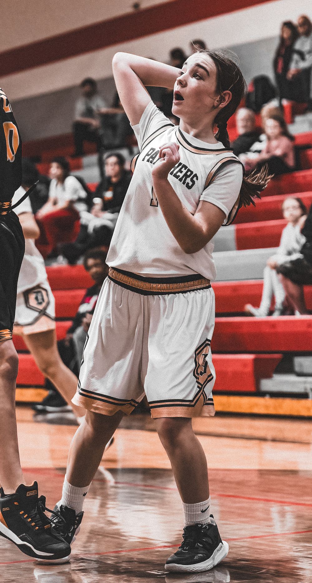 Basketball player in white uniform reacts emotionally during intense game moment.