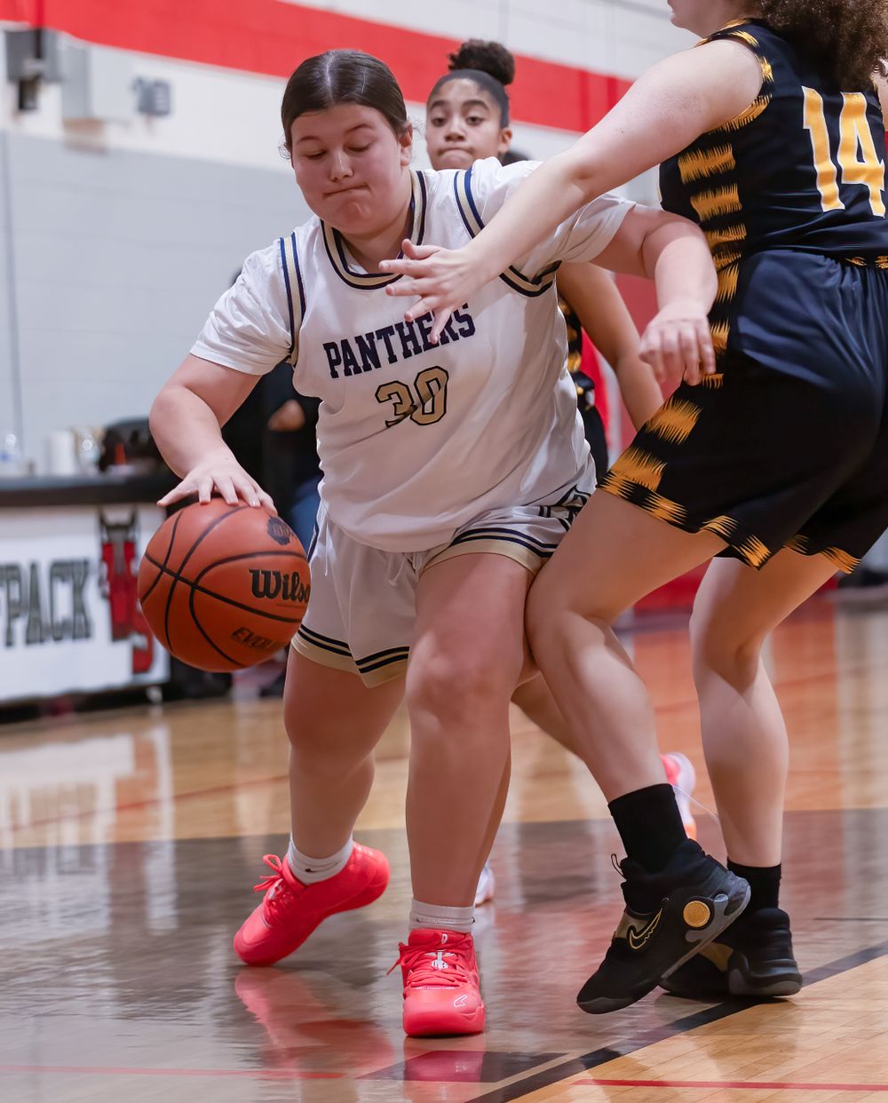 Basketball player dribbles while being closely defended during competitive game action.