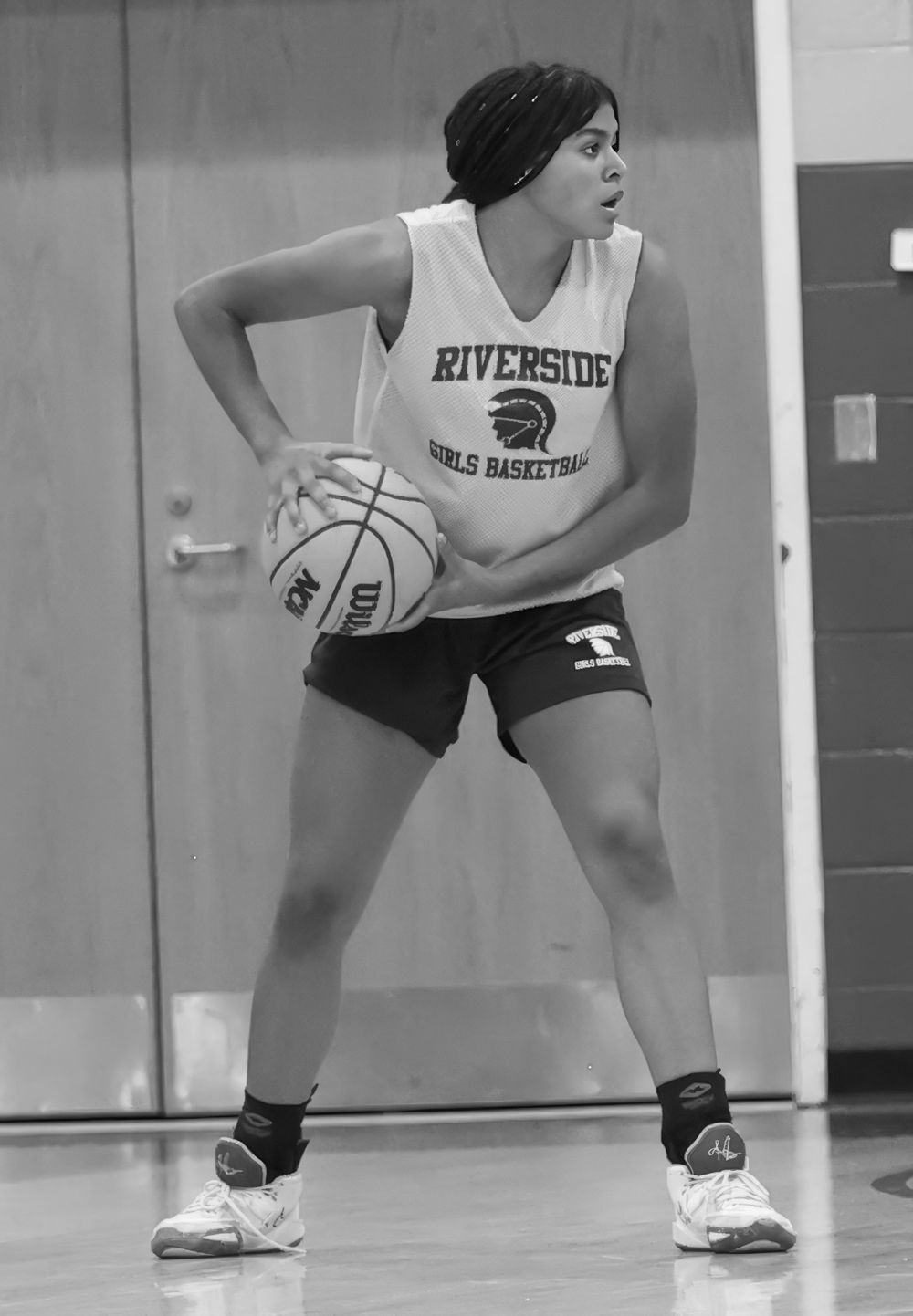 Basketball player in Riverside practice jersey maintains defensive stance during training.