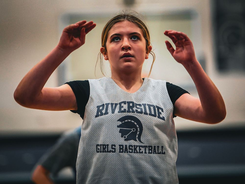 Basketball player in Riverside Girls Basketball jersey holds hands up during game practice.