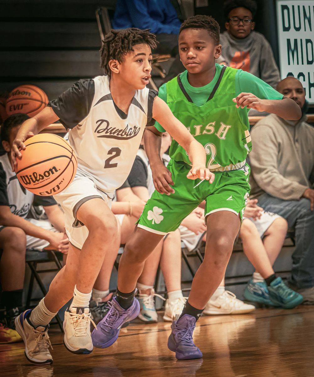 Two youth basketball players compete for possession during an intense game.