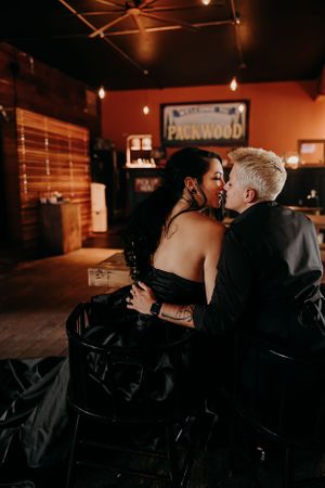 A romantic scene in a dimly lit bar with Packwood signage visible in the background.