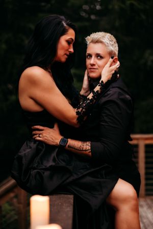 A couple in black attire shares an intimate moment during a romantic outdoor photoshoot.