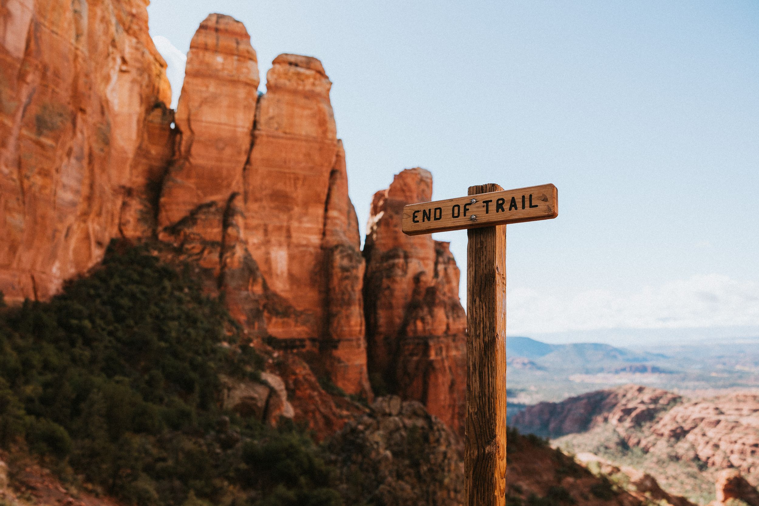 A wooden trail sign marks the path among towering red rock formations in Sedona.