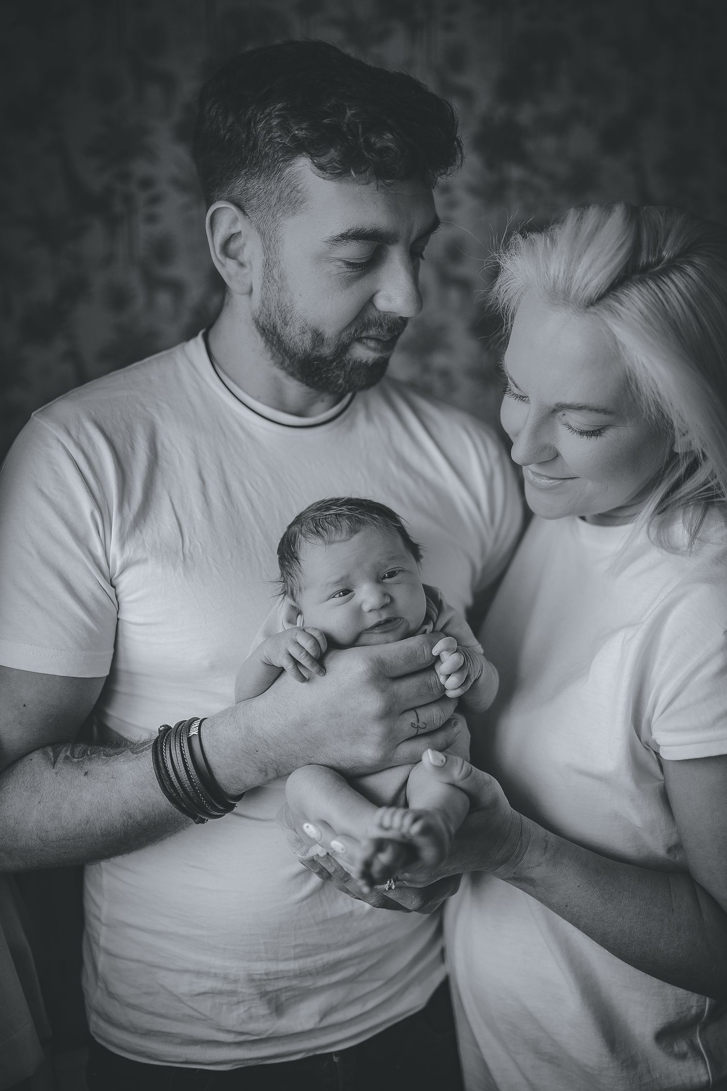 Parents in white shirts sharing tender moments with their newborn in black and white photography.  Photographer. Hull. East Yorkshire. Photo