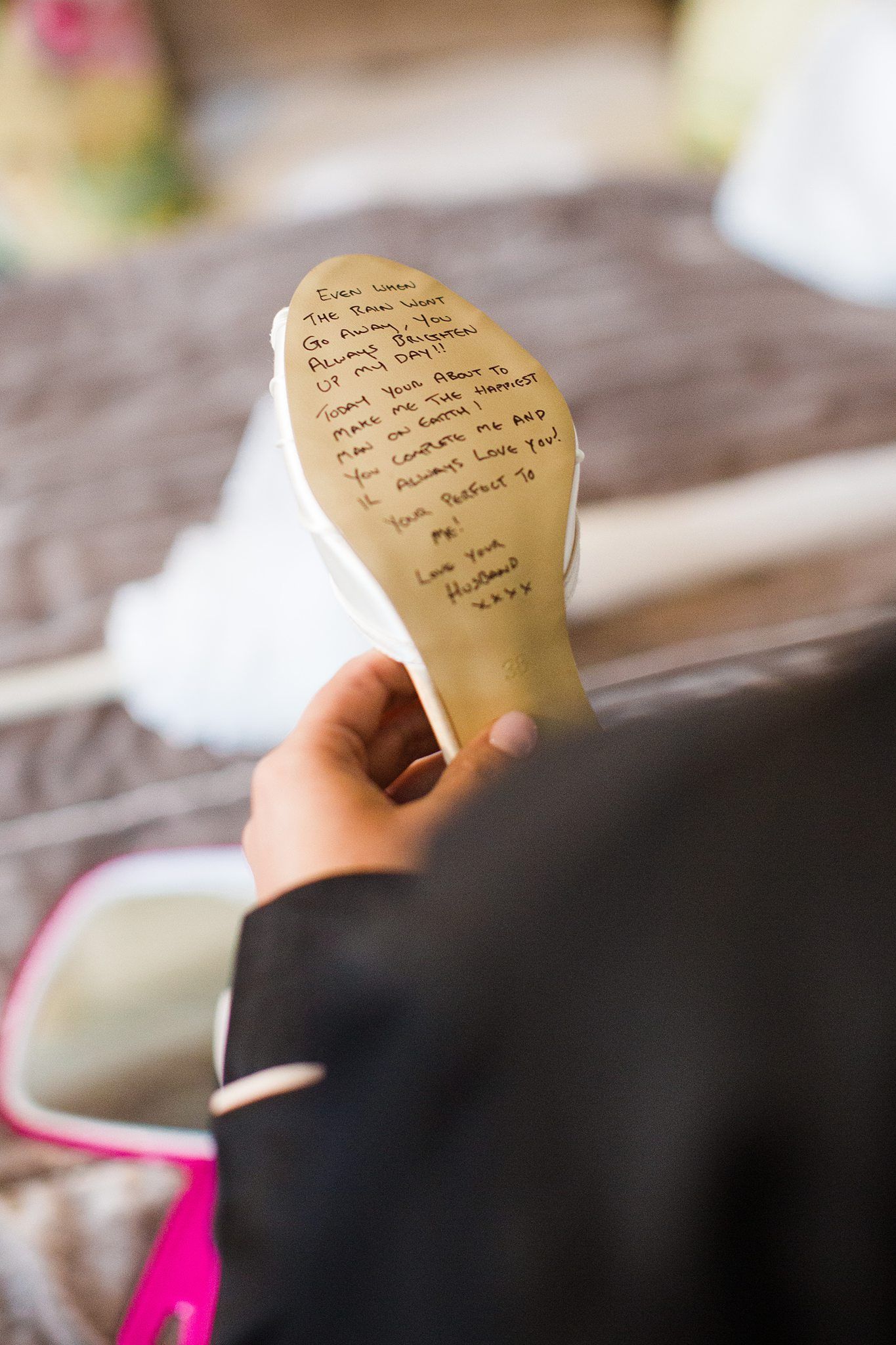 A handwritten note is visible on the sole of a wedding shoe held by someone wearing a black sleeve at Whitepoint Resort, Nova Scotia