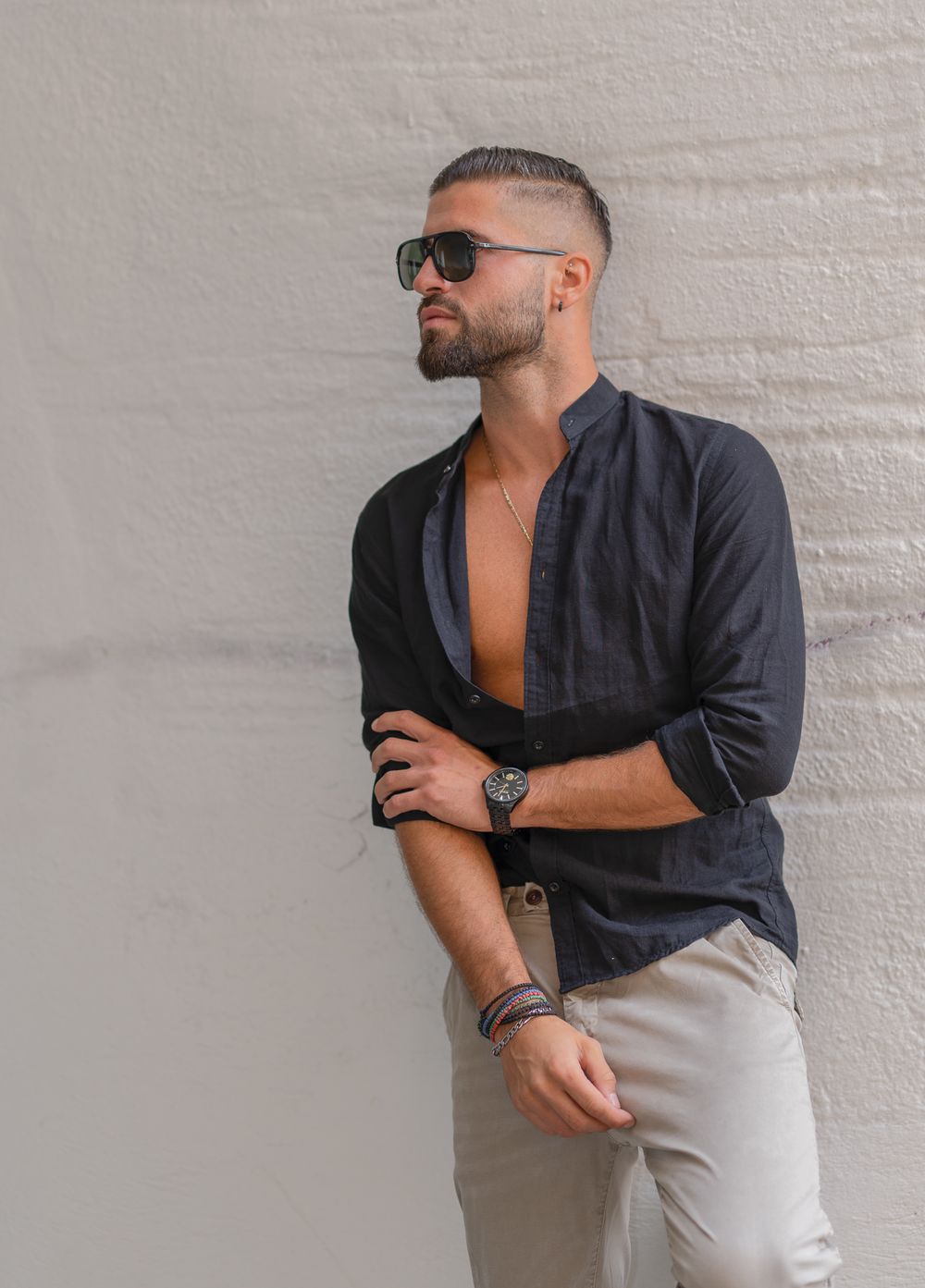 Menfotografie - Stylish man in a shirt and pants poses against white wall outdoors.