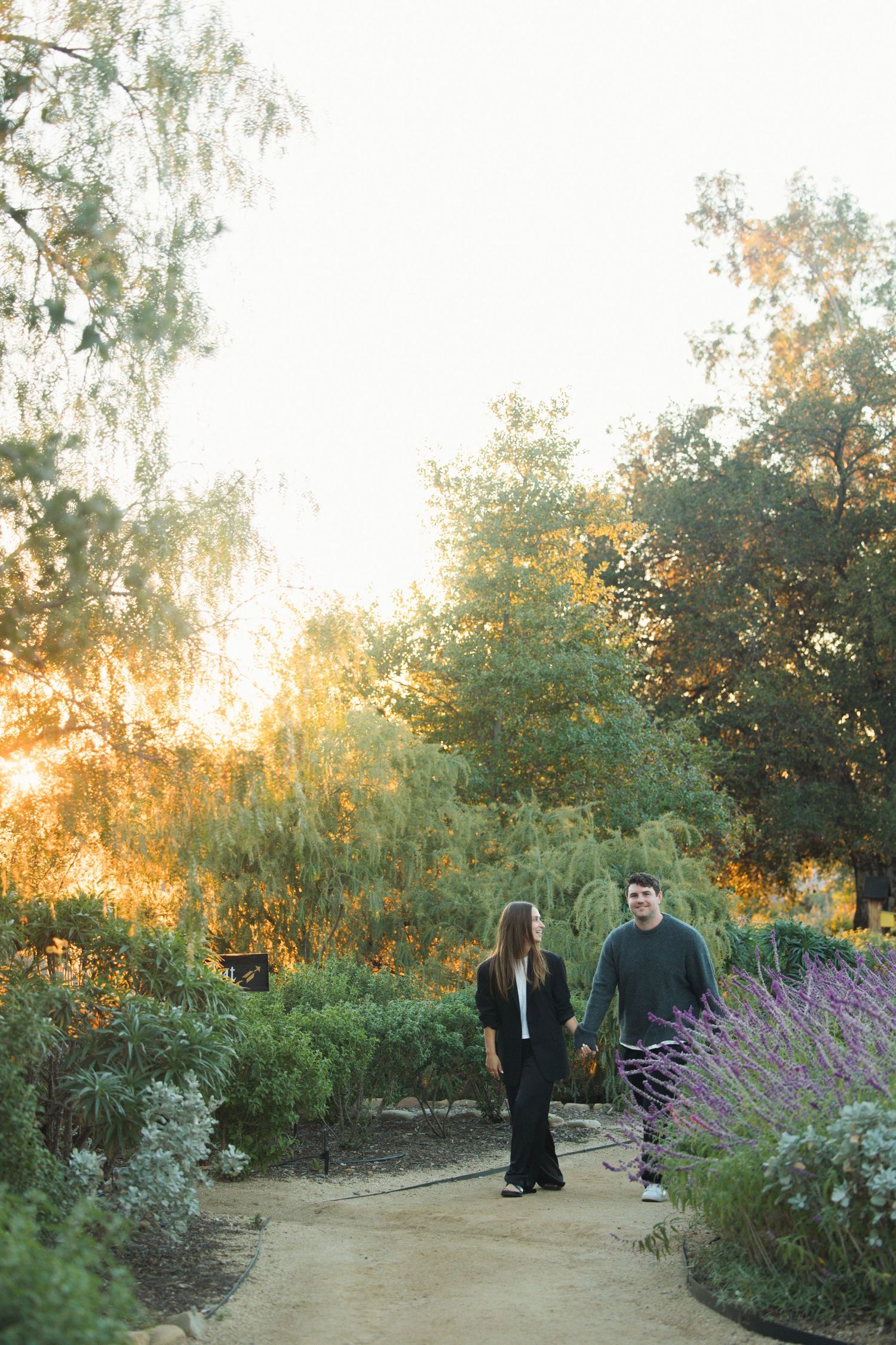 Couple walking through the gardens at Meditation Mount in Ojai during golden hour proposal