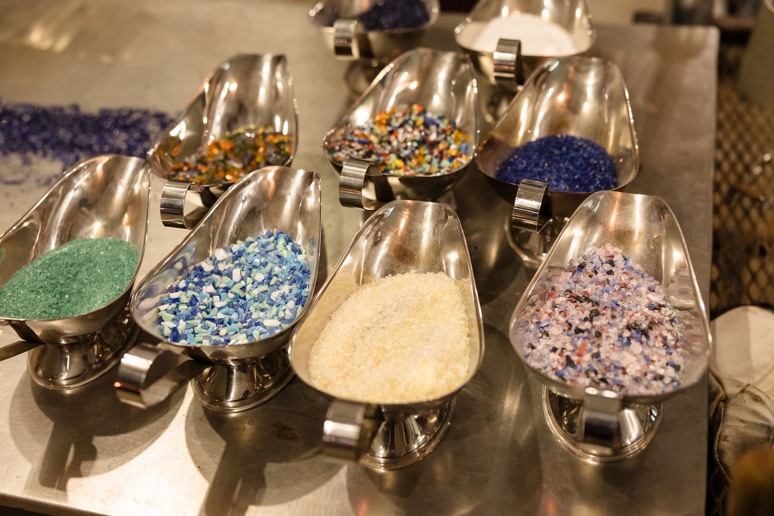Crystal chandelier parts and glass beads in various colors displayed on a workbench for custom lighting assembly.