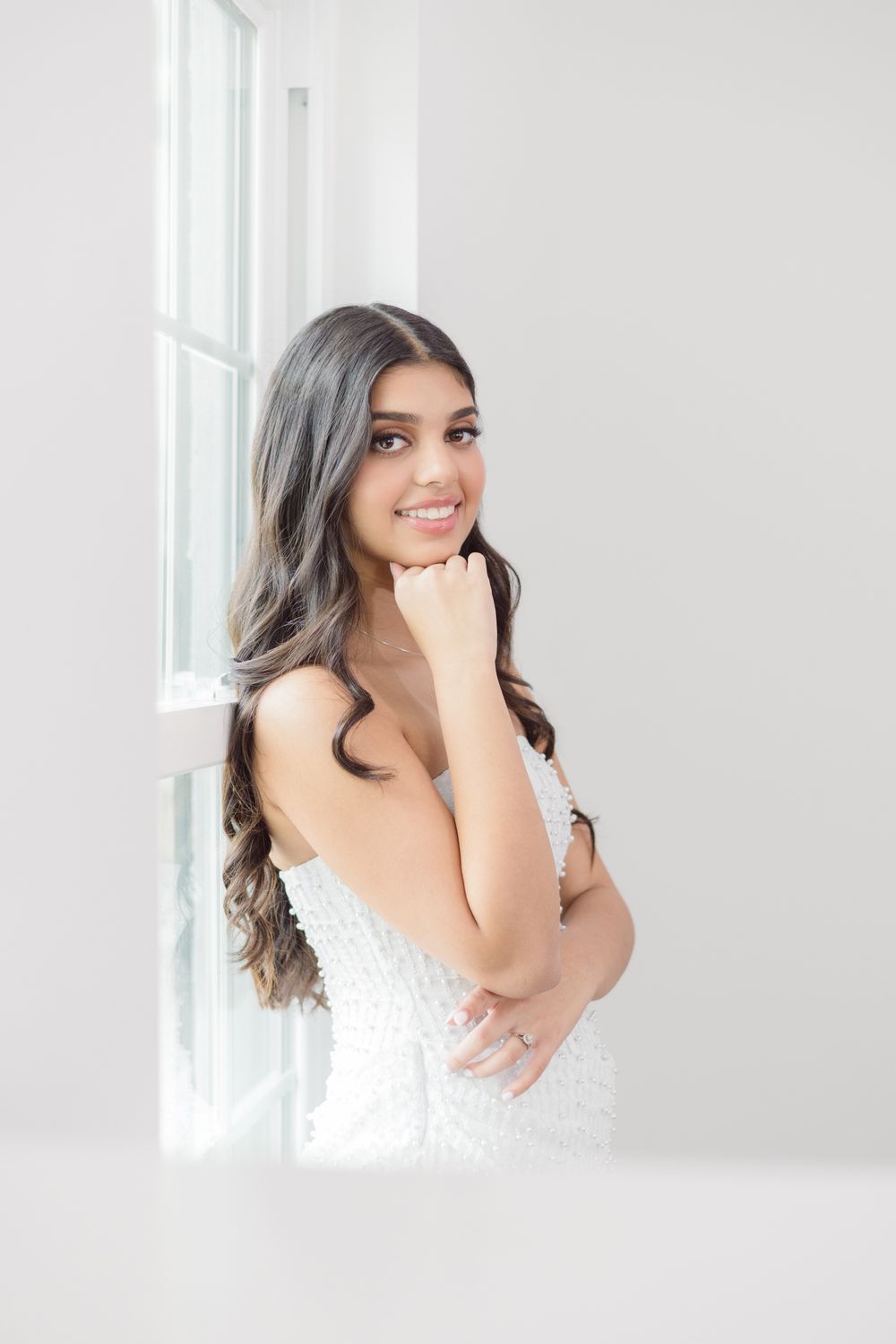 Portrait session in a bright white studio featuring soft romantic poses near a window.