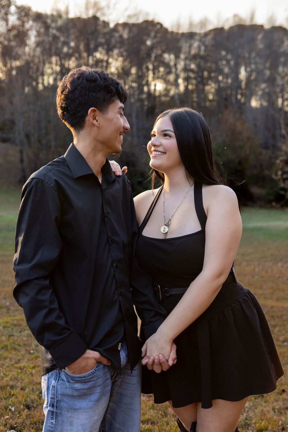 Happy young couple holding hands and gazing at each other lovingly in an outdoor autumn setting.