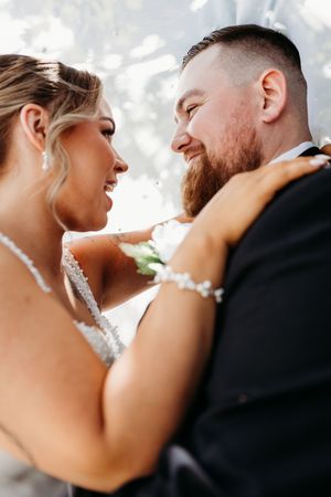 Laughing bride and smiling bearded groom share a joyful close moment on their wedding day.