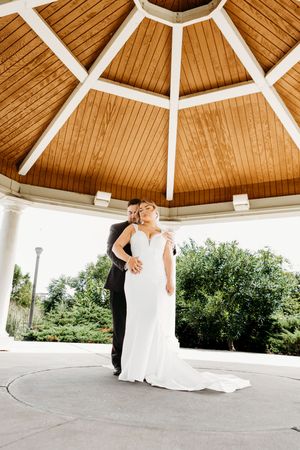 Bride and groom embrace romantically beneath a stunning wooden domed gazebo on their wedding day.