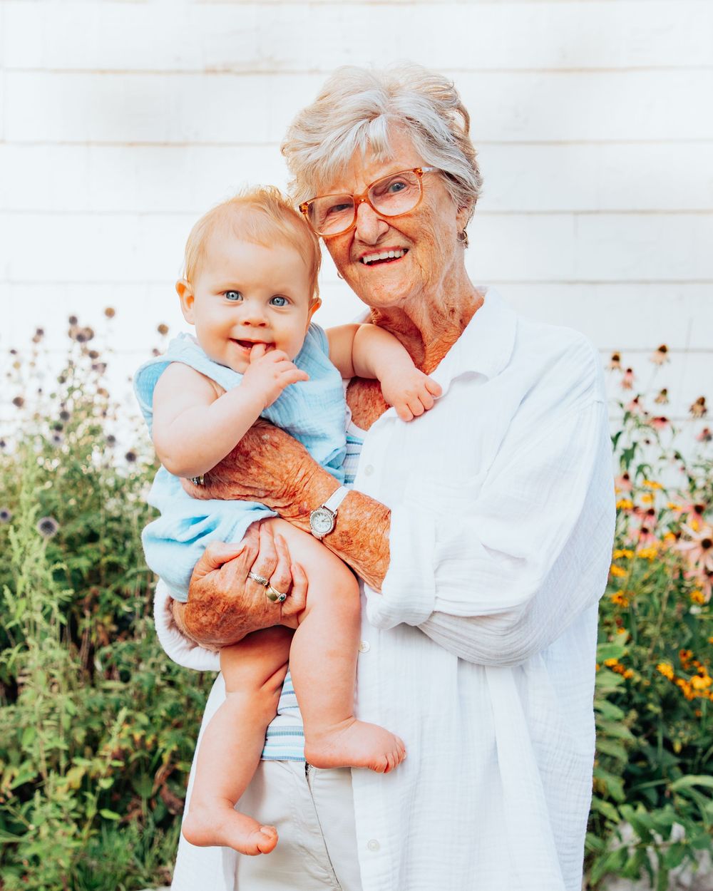 A joyful moment shared between a young child and elder in a garden with orange flowers.