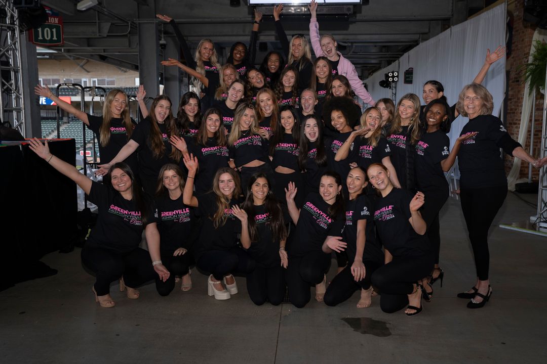 A group of dancers in black outfits pose together during a dance studio performance or rehearsal.