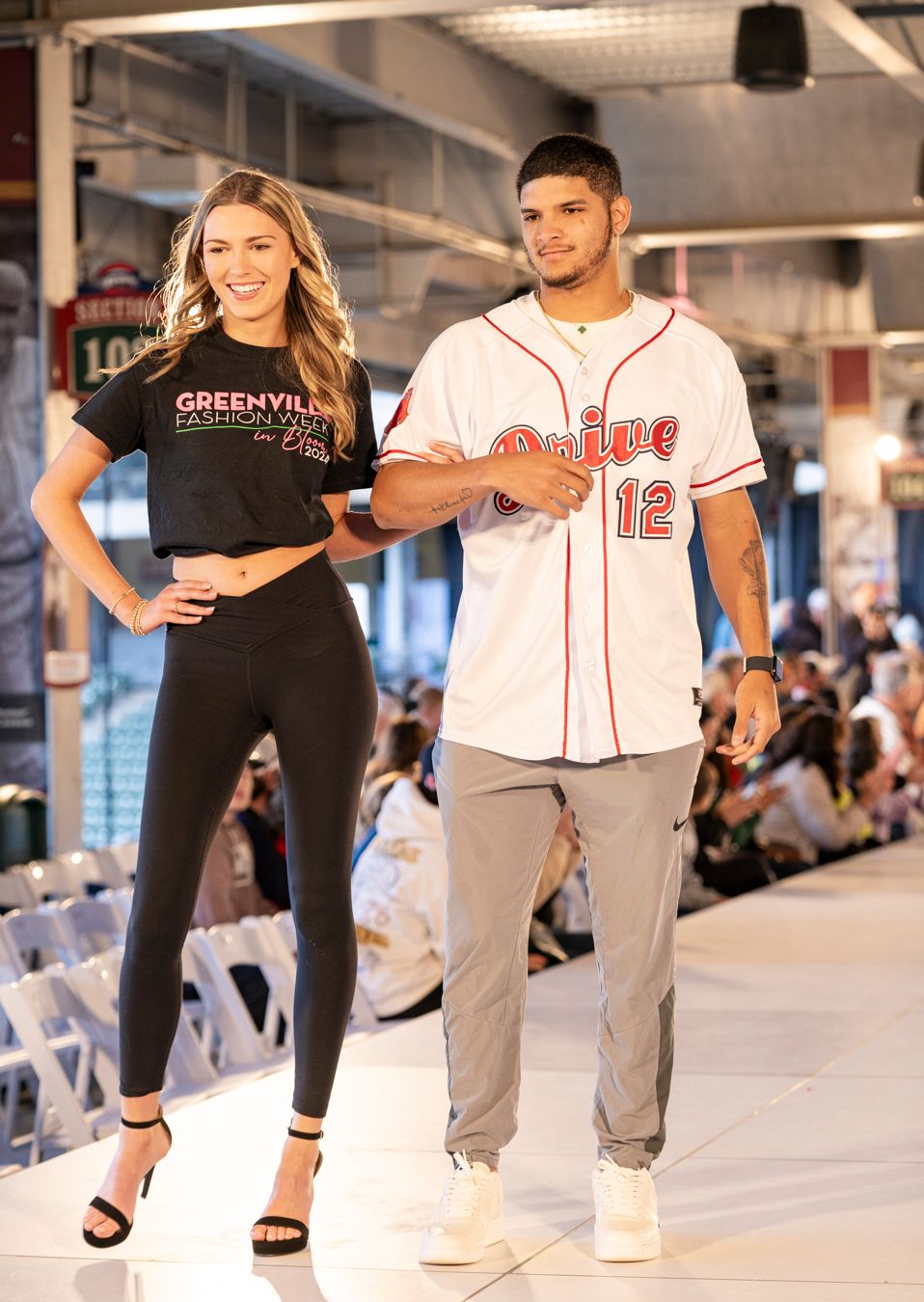 Models walk the runway wearing casual urban streetwear including baseball jerseys and athleisure at a fashion show.