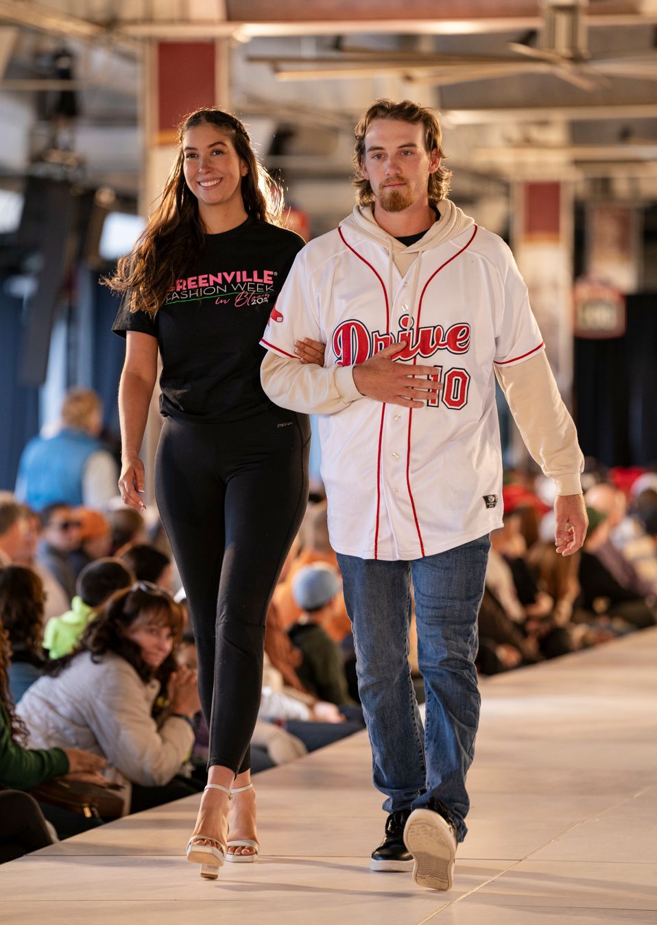 Models display sporty streetwear looks featuring baseball jerseys and black casual wear on the runway.