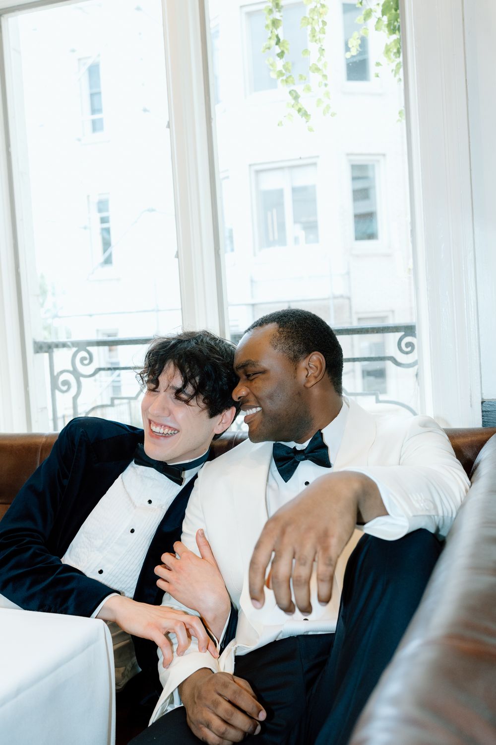 Two people in formal attire share a tender moment while relaxing on a couch together.