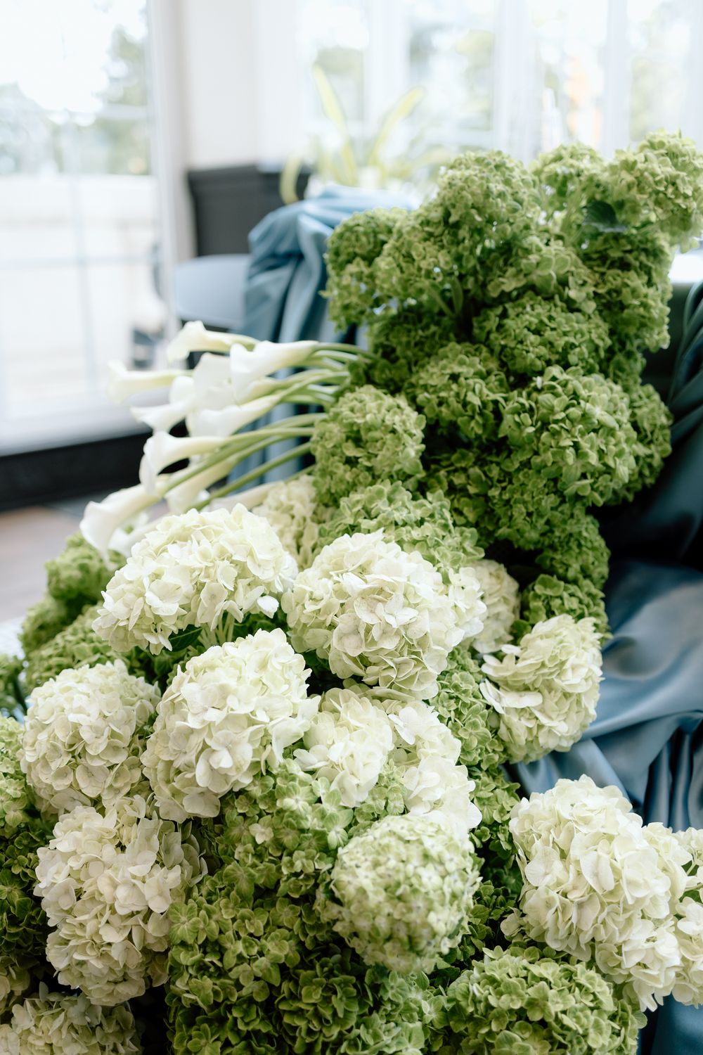 Fresh white hydrangea flowers with green leaves arranged in a decorative display against a dark background.