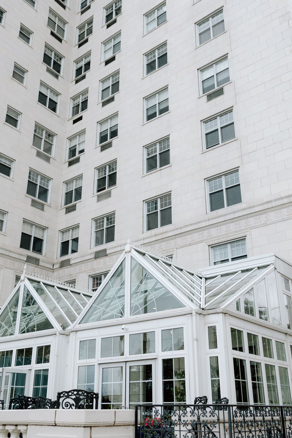 Modern white building exterior with glass conservatory and geometric window patterns.