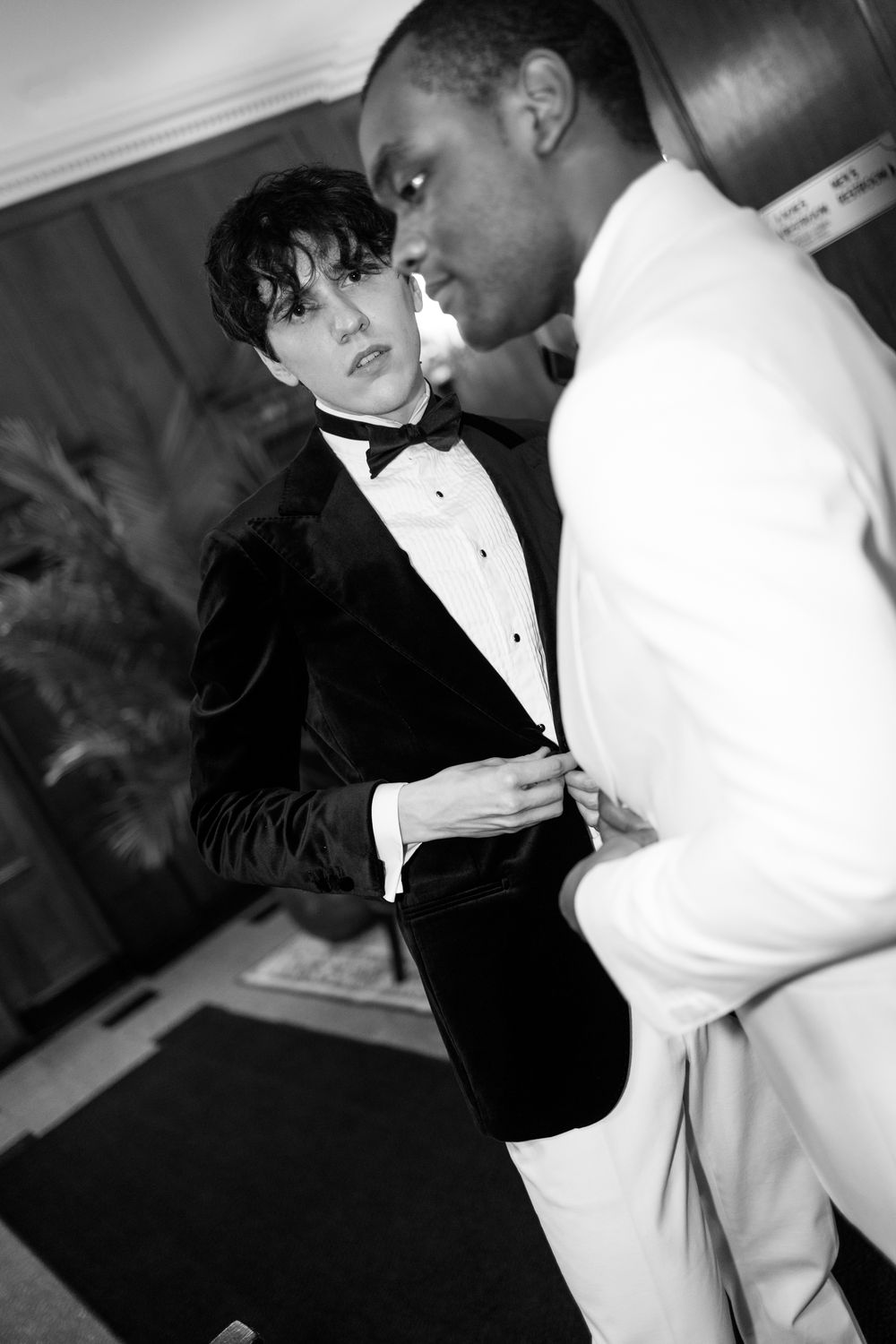 Black and white candid moments between wedding party members in formal attire.