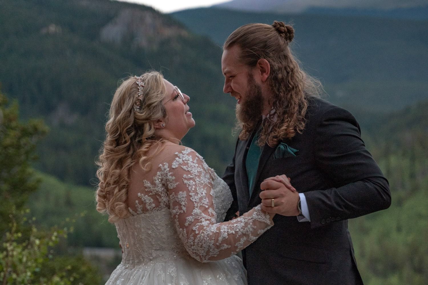 A couple shares an intimate dance moment at their mountain wedding, with scenic forest views in the background.